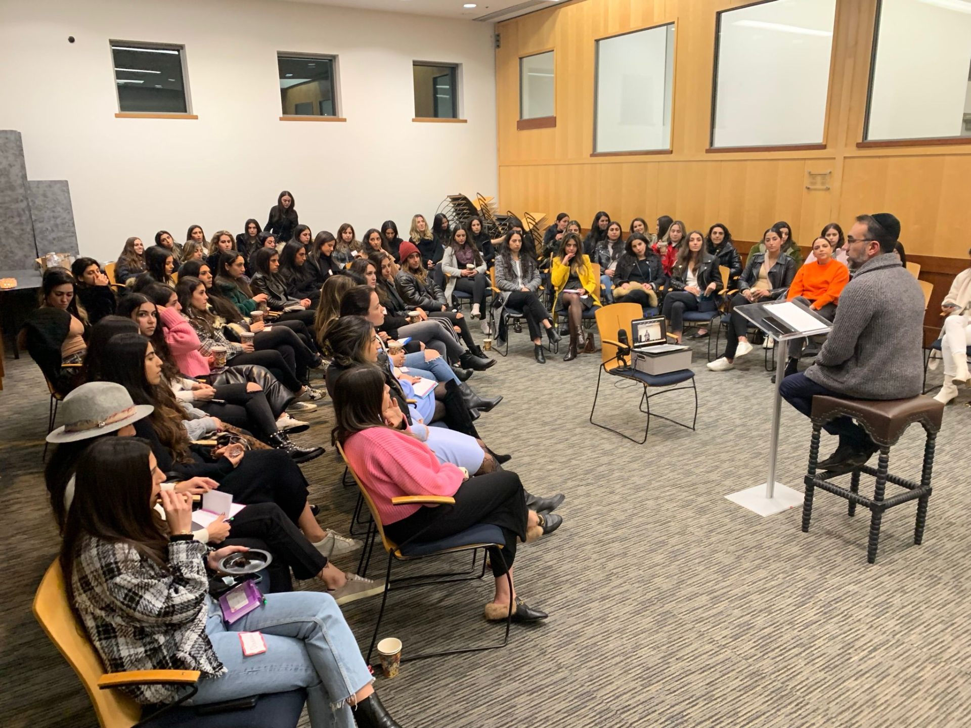 Rabbi Nissan teaching a large seated class of women